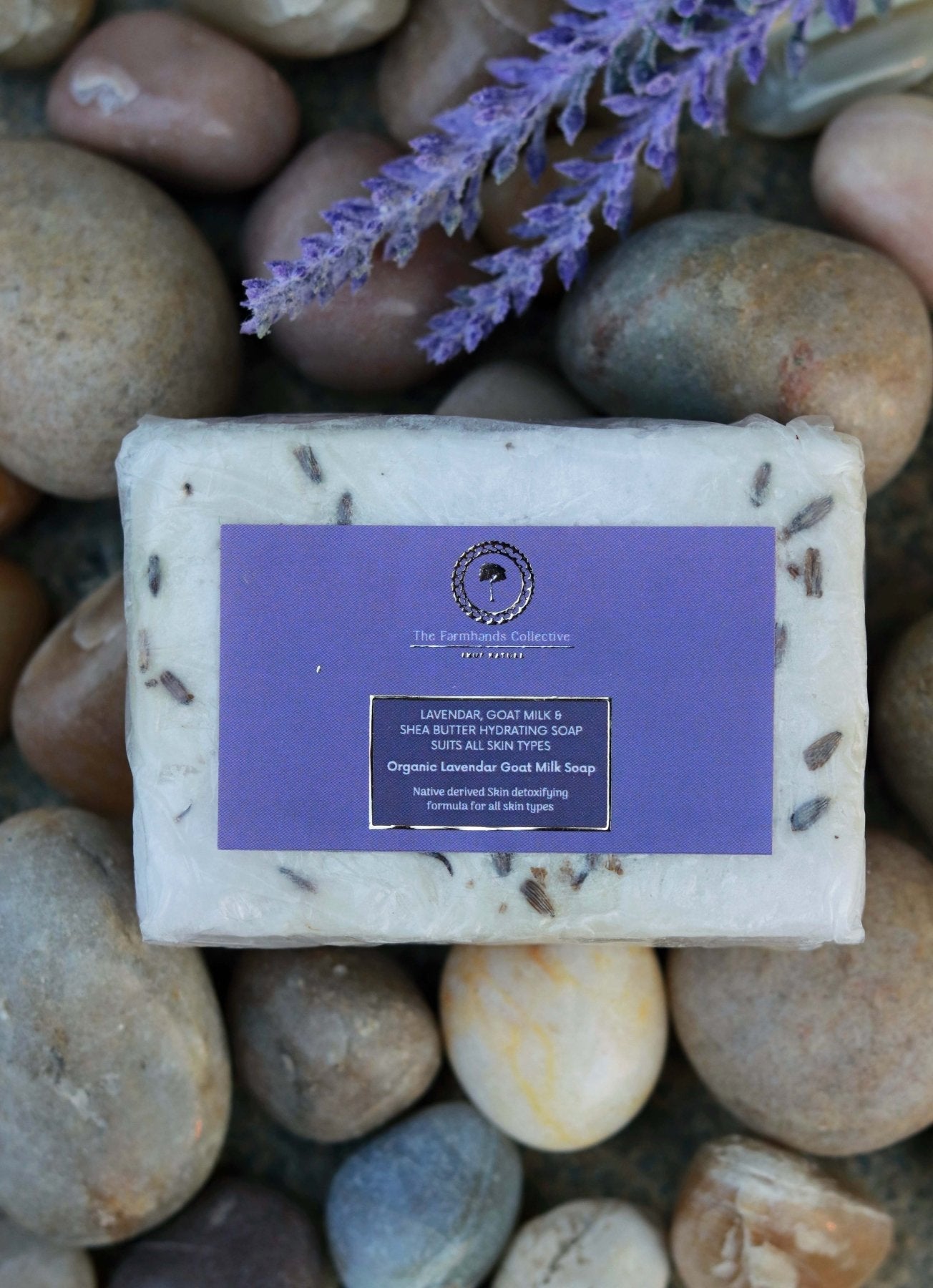 Flat lay of Kashmiri Lavender Goat Milk Soap from The Farmhands Collective resting on pebbles, showcasing the soap's rich texture and natural beauty. Highlights the luxurious, organic ingredients and its elegant presentation in a natural setting.